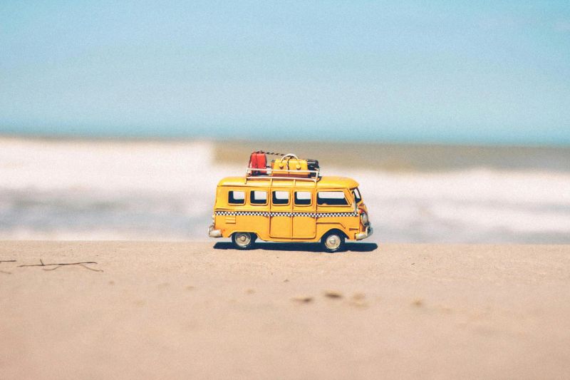 petit van jaune posé sur le sable avec la mer en fond invitant au road trip et à l'aventure