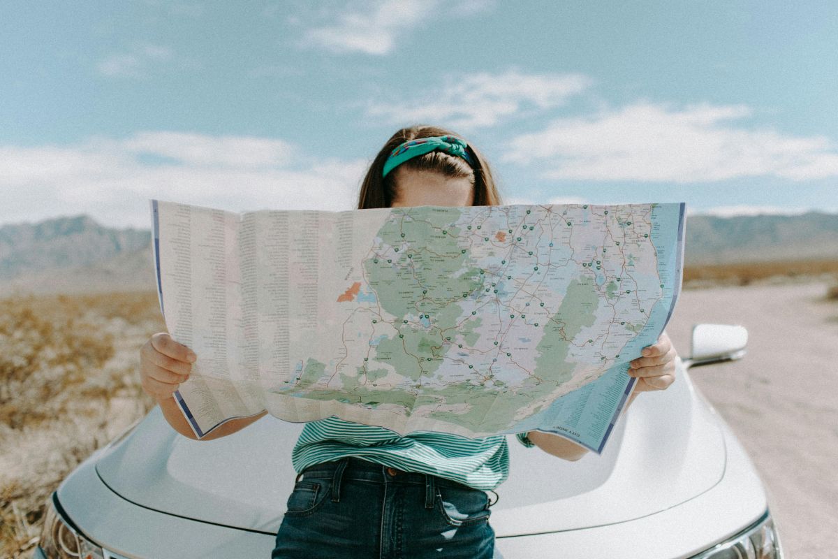 Femme faisant un road trip et lisant une carte routière dans un paysage désertique