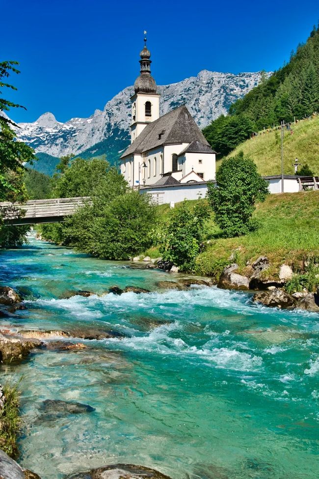 Paysage de montagne avec église surplombant une rivière pour des vacances sous le signe de la nature