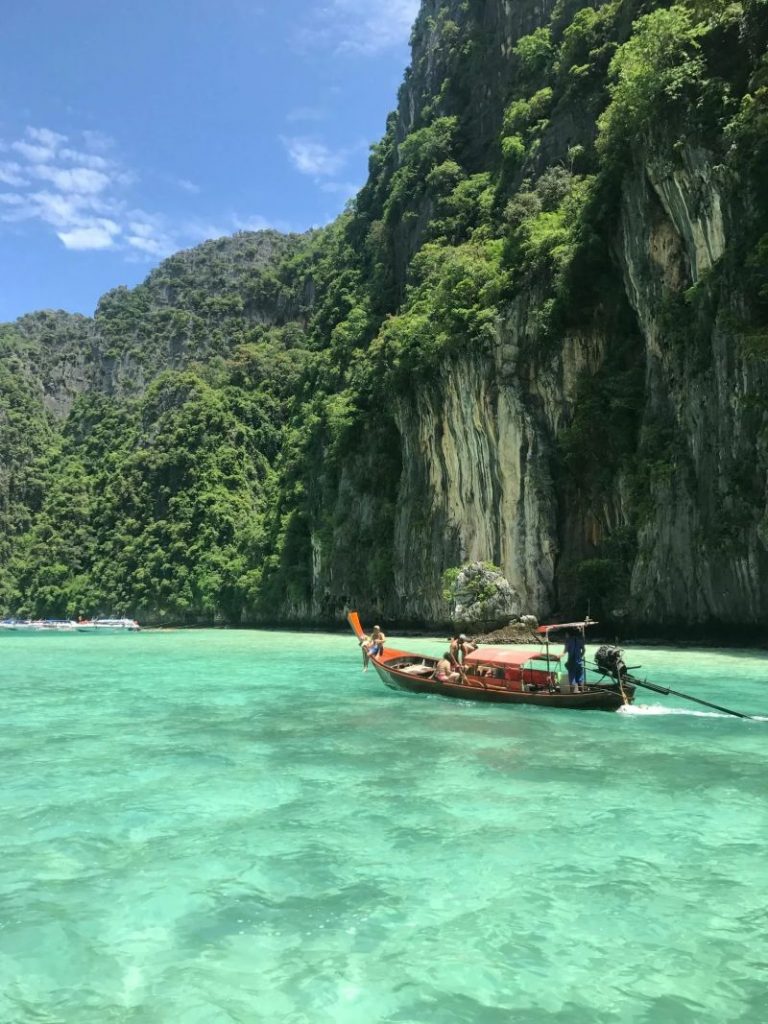 Vue panoramique d'un bateau à longue queue traditionnel thaïlandais sur des eaux émeraude avec des falaises calcaires luxuriantes en Thaïlande