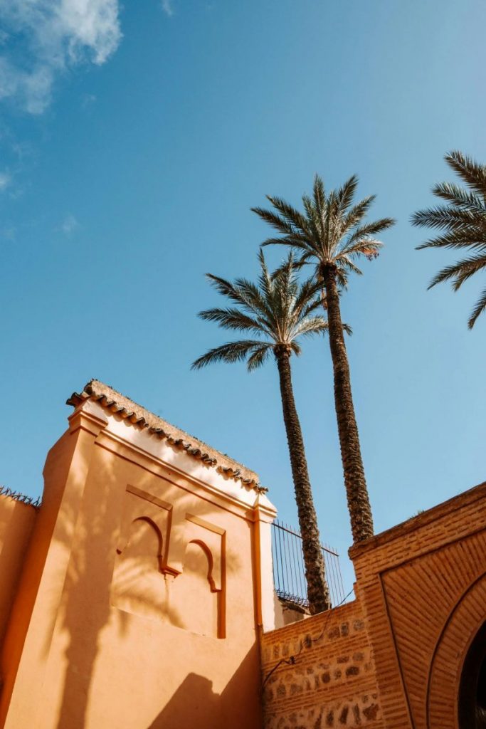 Découvrez l'architecture traditionnelle vibrante de Marrakech avec ses palmiers imposants sous un ciel bleu clair.